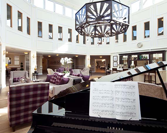Piano and lounge seats in the atrium at Beaumont Manor Care Home