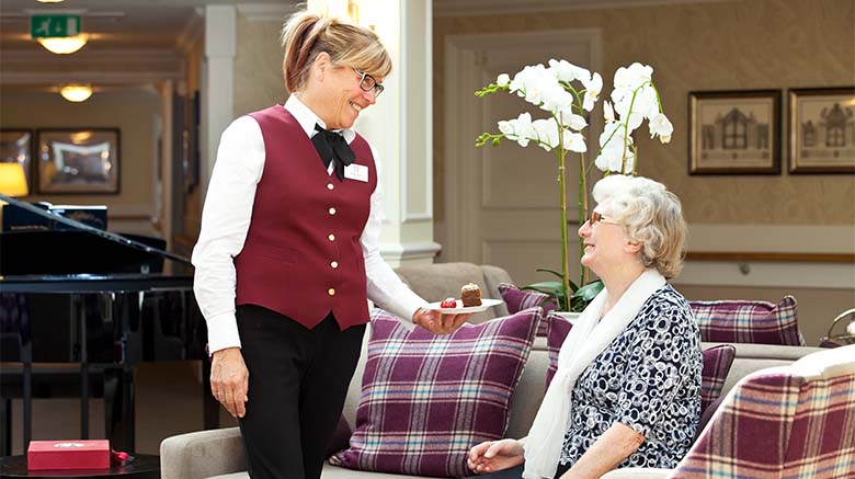 Beaumont Manor Care Home staff member offering resident a cake