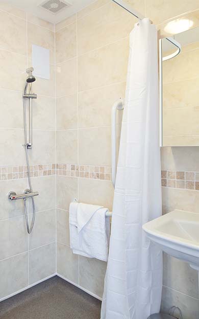 A wet room with shower curtain and towel at Beaumont Manor Care Home