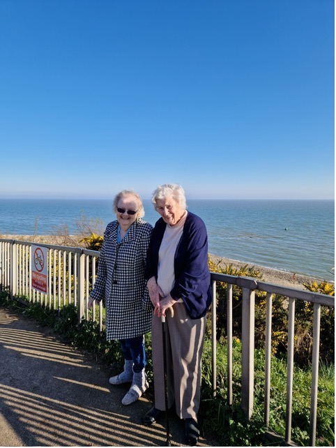 two female residents standing by a green railing with the beach in the background