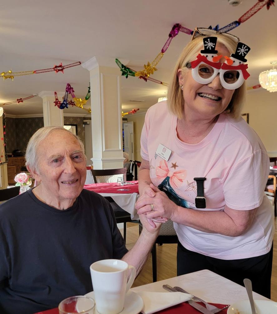resident and staff member smiling in christmas wear